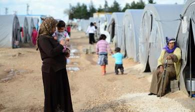 A woman st和s holding her child at a Syrian refugee camp in Turkey.